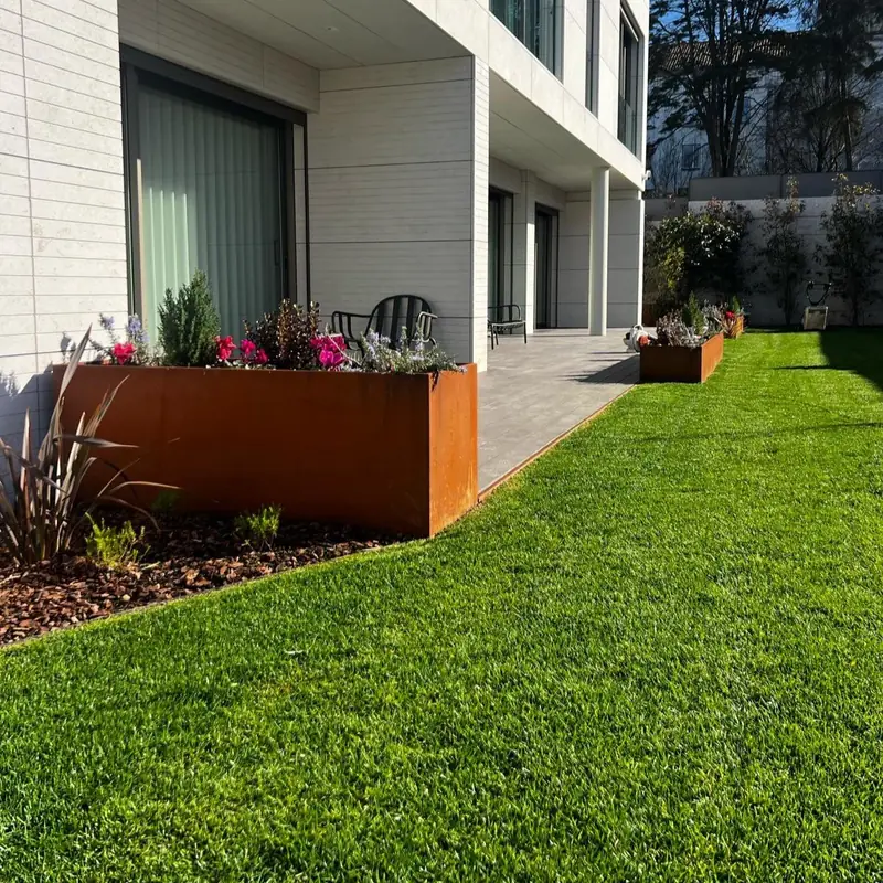 Freshly laid roll turf meeting a Corten steel planter in front of a modern building.