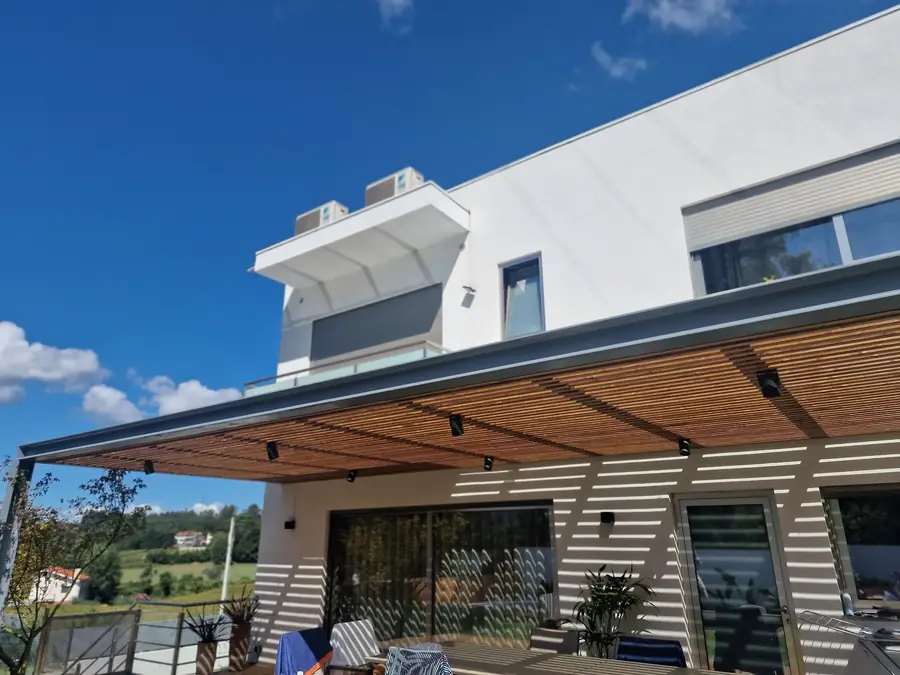 A white modern house with a steel pergola over the terrace, looking out across open countryside.